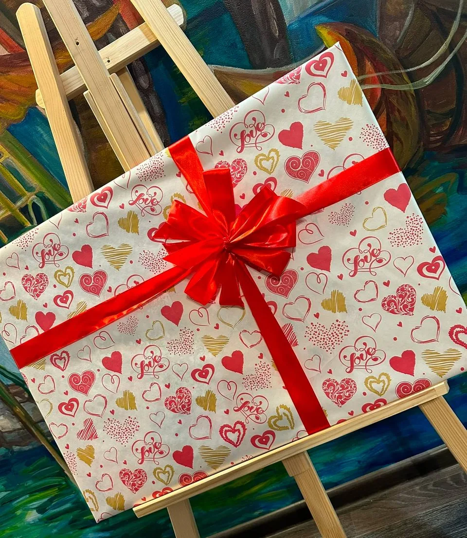 Подарок в упаковочной бумаге с сердечками «Love» и красной лентой